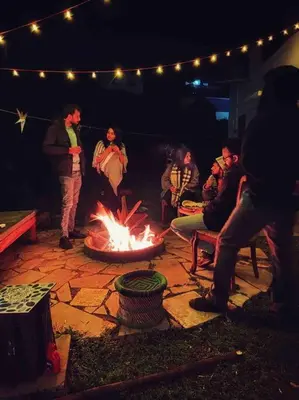 a group of people sitting around a fire pit at night at Nama-Stay - An escape villa in Ooty