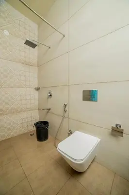 a white toilet in a bathroom with a shower at Sri Vidhya Residency by Indo Stays in Kotagiri