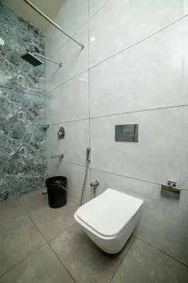a white toilet in a bathroom with a shower at Sri Vidhya Residency by Indo Stays in Kotagiri