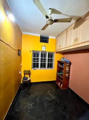 a room with a ceiling fan and a yellow wall at Chamundi_Temple-Hill View. in Mysore
