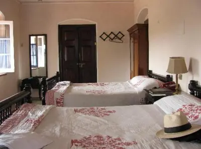 a bedroom with two beds with a hat on top at The Green Hotel in Mysore