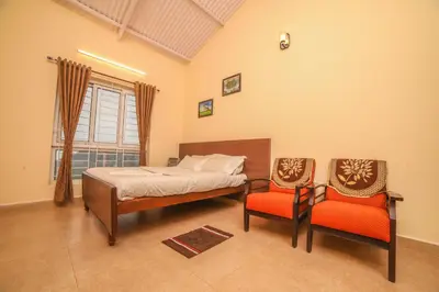 a bedroom with a bed and two chairs at The Springs by Indo Stays in Yedapalli