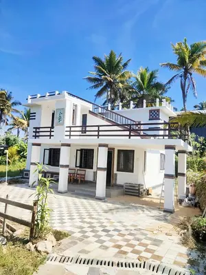a white house with palm trees in the background at Villas in Sultan Bathery