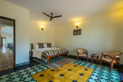 a bedroom with a bed and two chairs in a room at ama Stays & Trails Anjanagiri , Kotagiri in Kotagiri