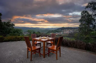a wooden table and chairs on a patio with a view at StayVista at Little Heaven with Breakfast in Ooty