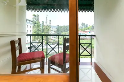 a room with two chairs and a balcony with a view at Le Celestium in Munnar