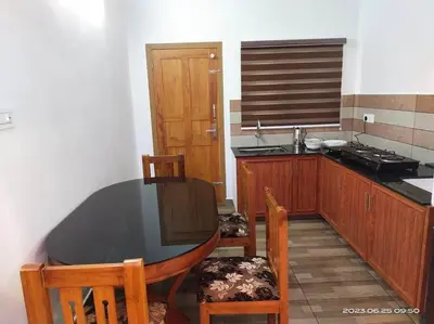a kitchen with a table and chairs and a sink at Merlys Fruit Garden - Resort at Thattekkad in Kotamangalam