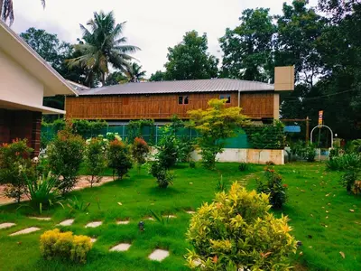 a house with a green yard in front of it at Merlys Fruit Garden - Resort at Thattekkad in Kotamangalam