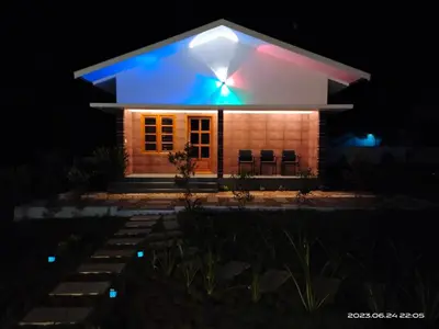a house lit up at night with blue lights at Merlys Fruit Garden - Resort at Thattekkad in Kotamangalam