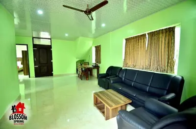 a living room with a couch and a table at Blossom Spring Villa in Ooty