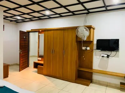a room with a flat screen tv and wooden cabinets at Regalia Wayanad in Kalpetta