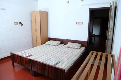 a small room with a bed and a bench in it at Ocean Green Kerala in Kannur