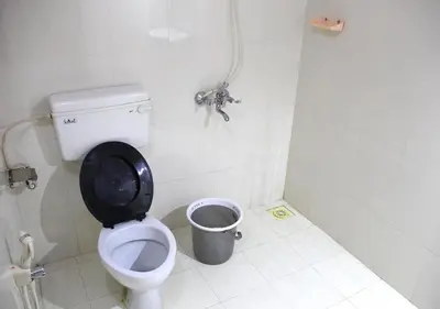 a bathroom with a toilet and a trash can at Ocean Green Kerala in Kannur