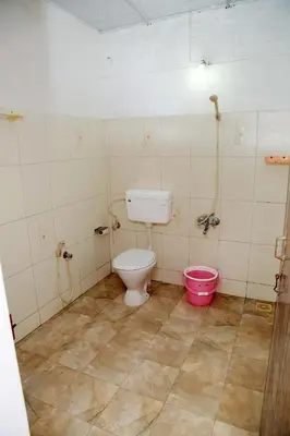 a bathroom with a toilet and a pink bucket at Ocean Green Kerala in Kannur