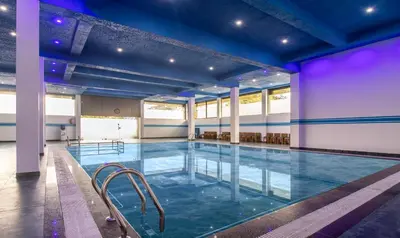 a large indoor pool with blue lighting in a building at Treebo The Rove with Swimming Pool in Madikeri