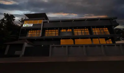 a black building with yellow windows and a cloudy sky at Treebo The Rove with Swimming Pool in Madikeri
