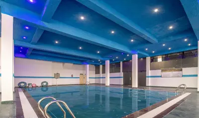 an indoor swimming pool with blue ceilings and chairs at Treebo The Rove with Swimming Pool in Madikeri