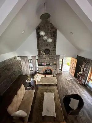 a large living room with a stone fireplace at Captain's Cabin in Masinagudi