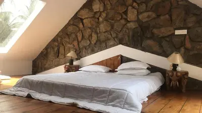 a bed in a room with a stone wall at Captain's Cabin in Masinagudi