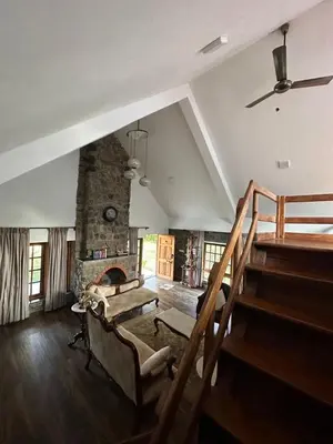 a living room with stairs and a stone fireplace at Captain's Cabin in Masinagudi