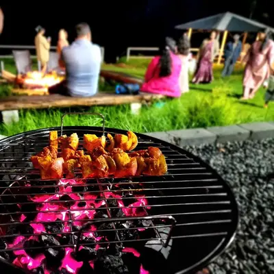 a grill with food on it with people in a park at Cloud & Mist Inn-Stay with Mountain Views in Kotagiri, Near Ooty in Kotagiri