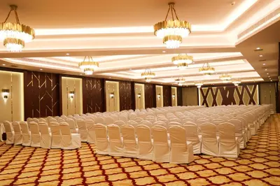 a large banquet hall with white chairs and chandeliers at Jenneys Residency in Coimbatore