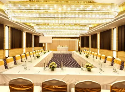 a large banquet hall with white tables and chairs at Jenneys Residency in Coimbatore