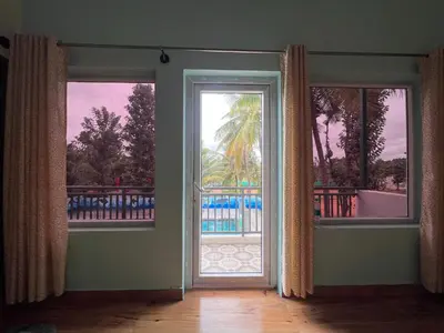 an empty room with a door leading to a balcony at Gandhada Goodu Retreat in Kanakapura