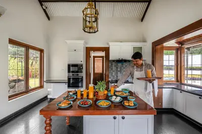 a man in a kitchen with a table of food at The Winterfel in Yedapalli