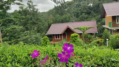 a house with purple flowers in the foreground at Don's River Valley Jungle Resort in Marayoor