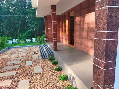 a house with a courtyard with rocks and plants at Family Cottage at Merlys Fruit Garden, Thattekkad in Kotamangalam
