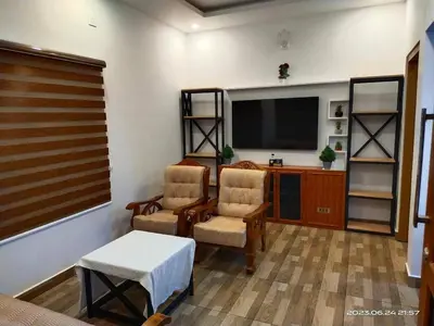 a living room with two chairs and a flat screen tv at Family Cottage at Merlys Fruit Garden, Thattekkad in Kotamangalam