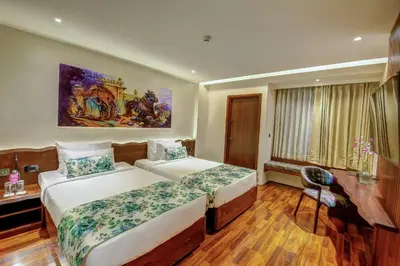 a hotel room with two beds and a desk at Regenta Central Javaji Mysore in Mysore