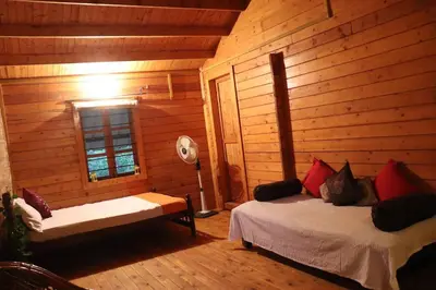 a room with two beds in a log cabin at Coorg Northbreeze Wooden Stay in Madikeri
