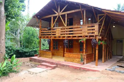 a small wooden house with a porch on a yard at Coorg Northbreeze Wooden Stay in Madikeri