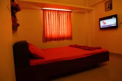 a bedroom with a bed with red sheets and a television at PRANOV RESIDENCY-Luxury in Coimbatore