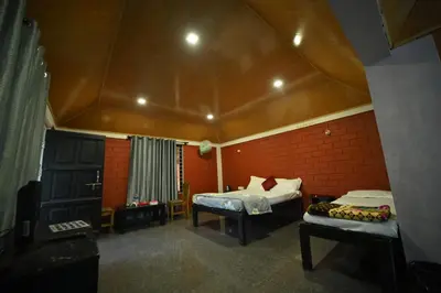 a bedroom with two beds in a room with a roof at Coorg HomeStay Resort in Kushālnagar