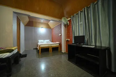 a room with a bedroom with a bed and a desk at Coorg HomeStay Resort in Kushālnagar