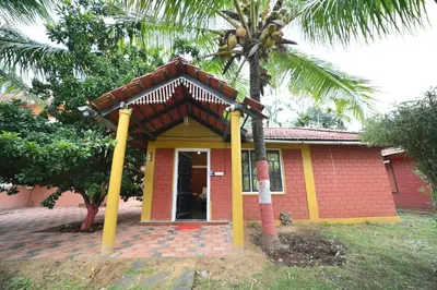 a small house with a palm tree in front of it at Coorg HomeStay Resort in Kushālnagar