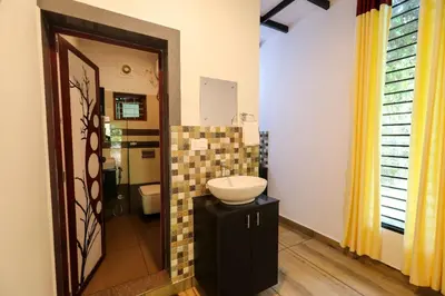 a bathroom with a sink and a toilet and a mirror at Agasthya Private Pool & Park villa in Sultan Bathery