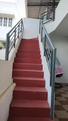 a staircase with red steps and a metal railing at Karimbummel House- A room with spacious Balcony in Mysore