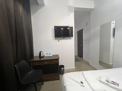 a room with a bed and a desk and a television at AROMA INN in Kalpetta