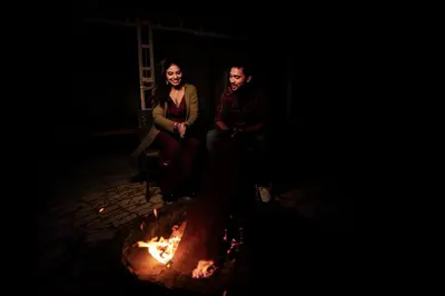 a man and a woman sitting next to a fire at Tulips Resorts - Elkhill in Ooty