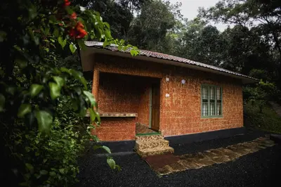 a red brick building with a door in a yard at Mahout Resort Wayanad - An Experiential Jungle Stay with Waterfall in Kalpetta