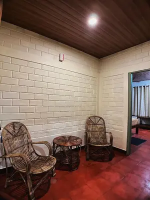 a room with three chairs and a table and a wall at Mahout Resort Wayanad - An Experiential Jungle Stay with Waterfall in Kalpetta