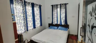 a small bedroom with blue and white curtains and a bed at Sandy 4 Bhk Homestay - Only Adults Allowed in Ooty
