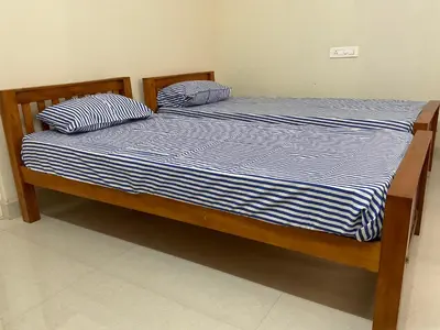 a bed with blue and white striped sheets and pillows at Shantham Service Apartments, Indumanagar, Coimbatore in Coimbatore