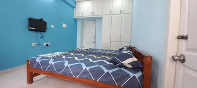 a bedroom with a bed with a blue wall at Shantham Service Apartments, Indumanagar, Coimbatore in Coimbatore