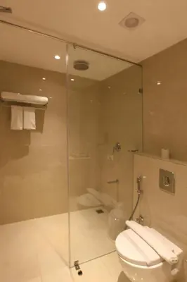 a bathroom with a glass shower and a toilet at PARK RESIDENCY ARCADIA in Alwaye