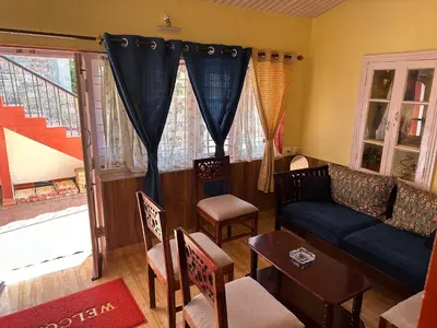 a living room with a couch and a table and chairs at Kanjira house in Ooty